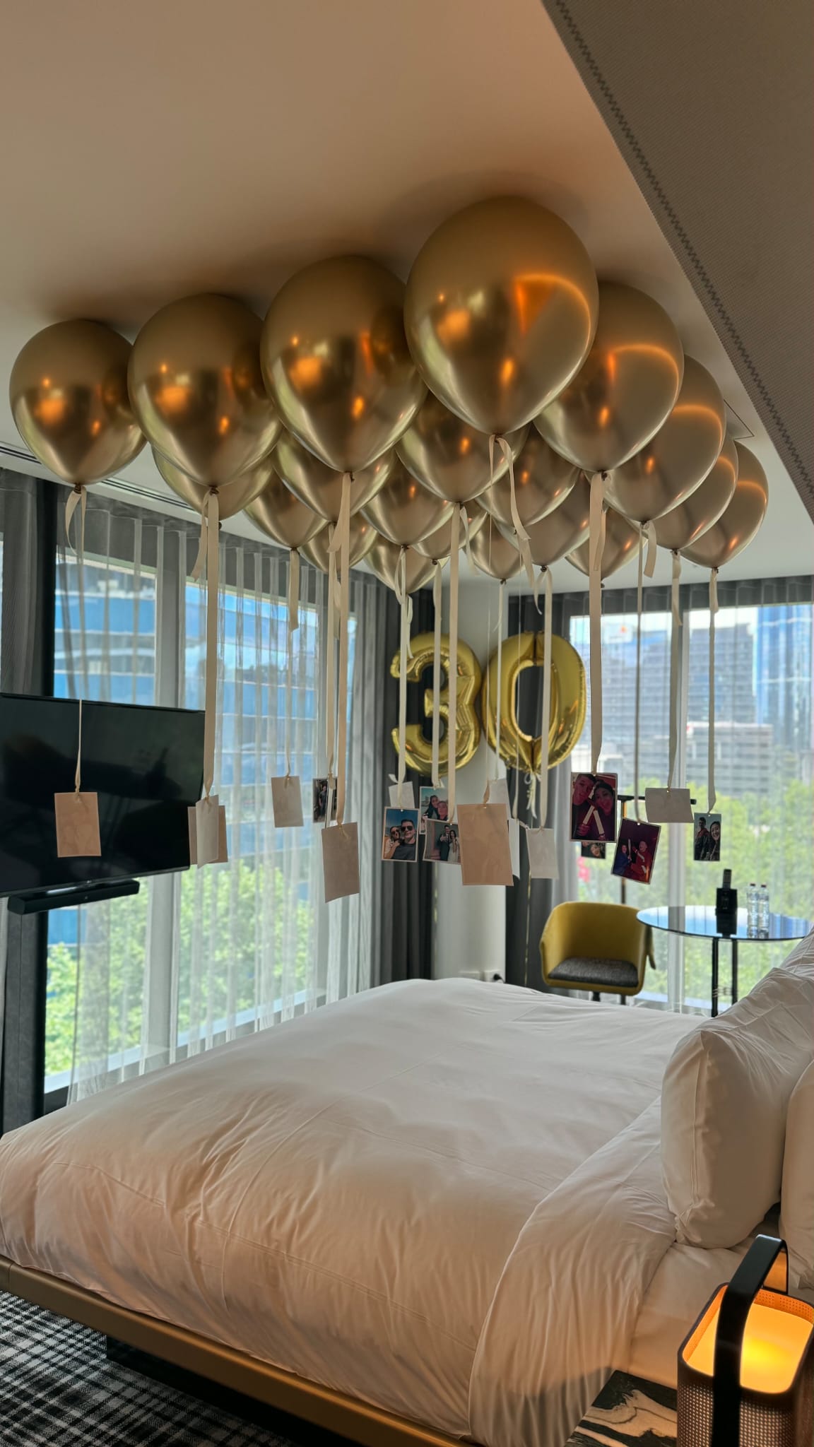 Decorative setup with gold balloons and '30' letter decorations in a room with large windows.