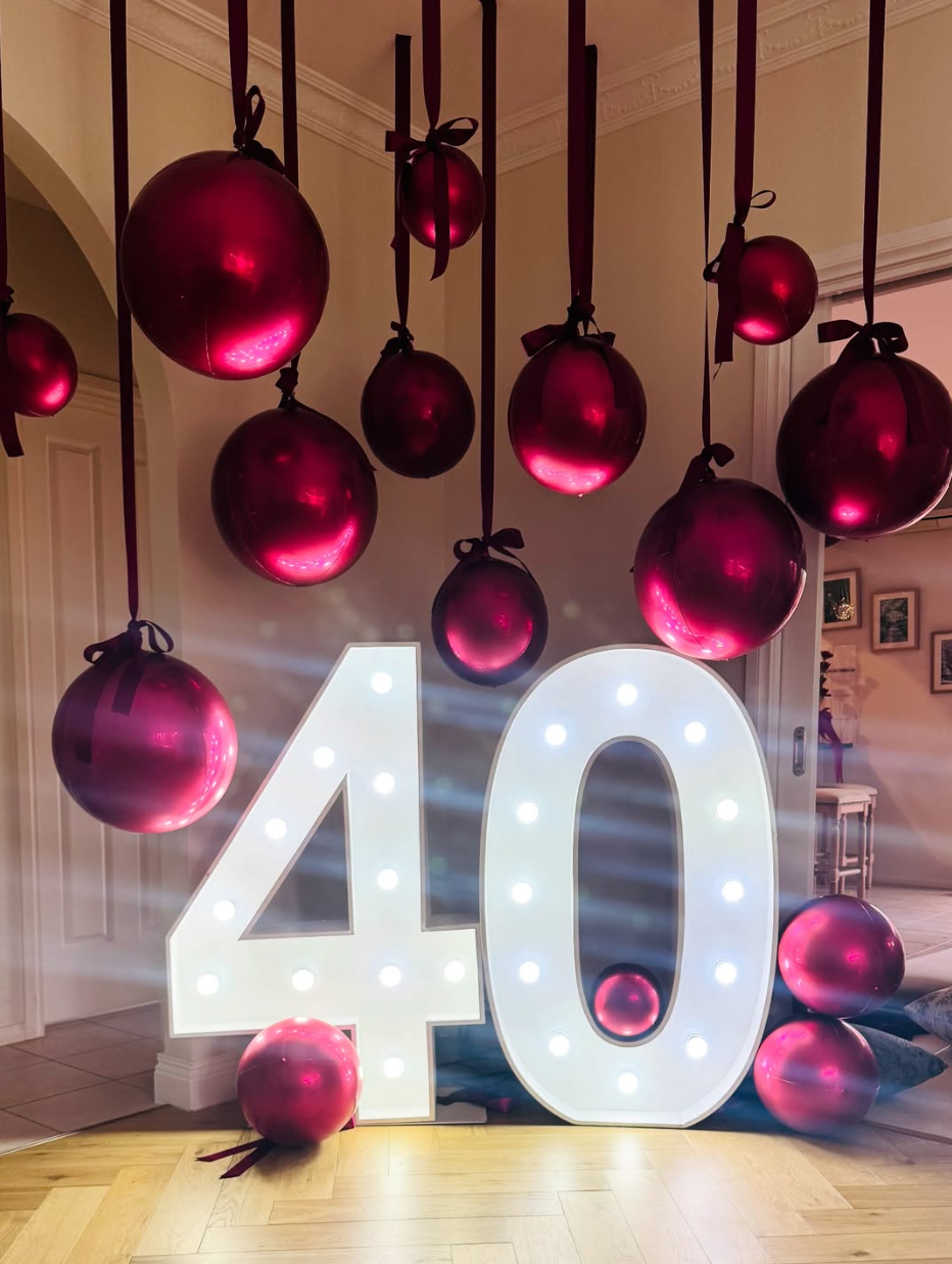 large metallic red balloons hanging from the ceiling by thick red ribbons with a light up number 40 sign in Cheltenham Victoria