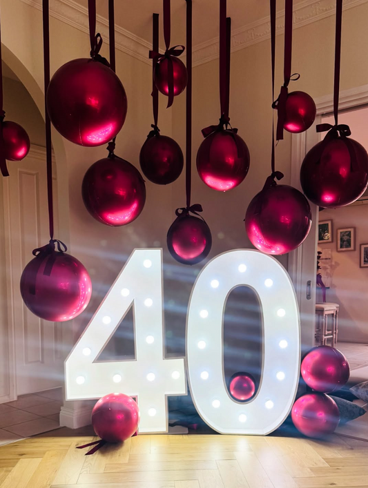 large metallic red balloons hanging from the ceiling by thick red ribbons with a light up number 40 sign in Cheltenham Victoria