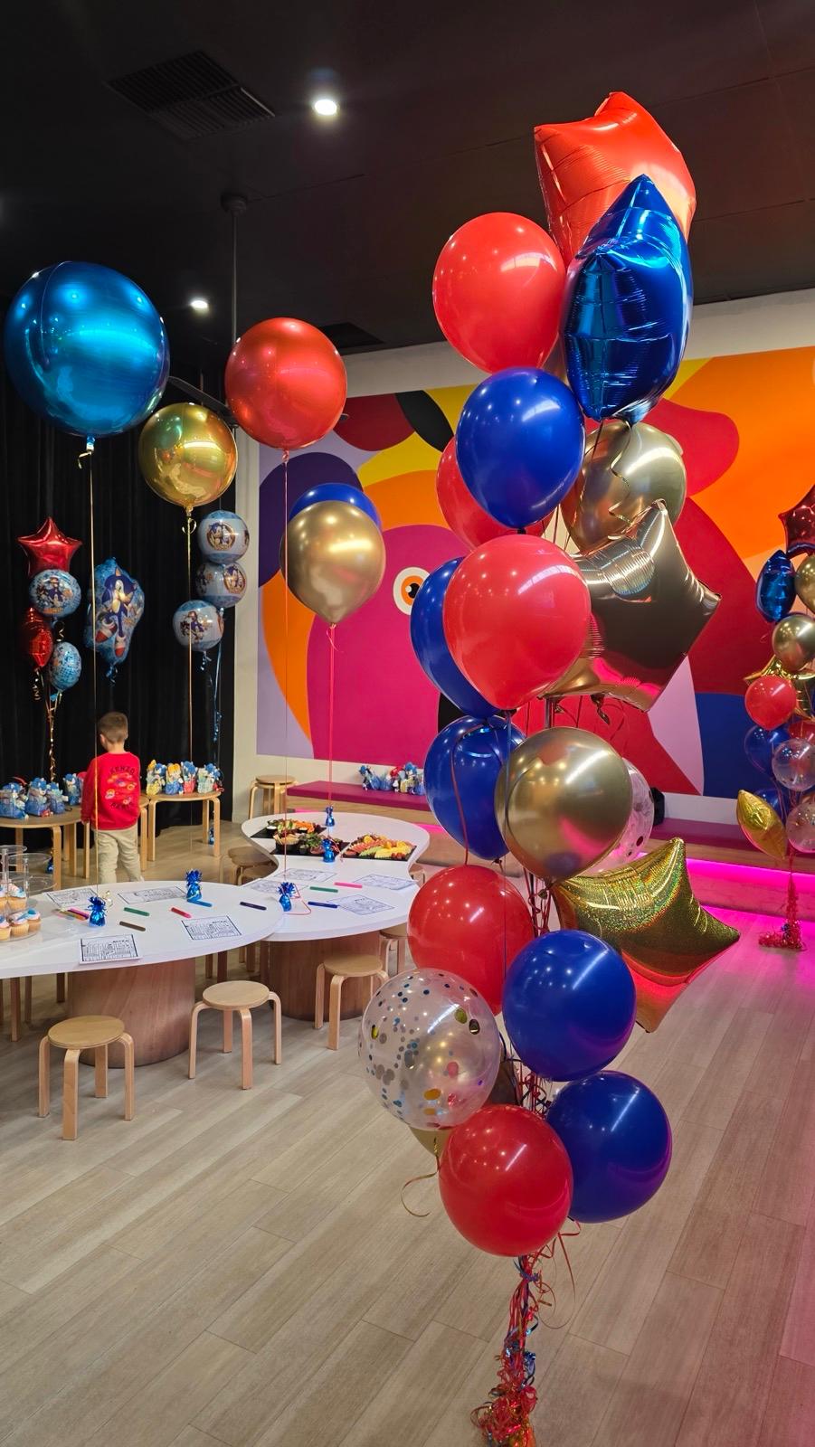 Colorful balloons in a room with tables and chairs, likely a party setup at MOPA Sandringham by Fairytale Balloons 