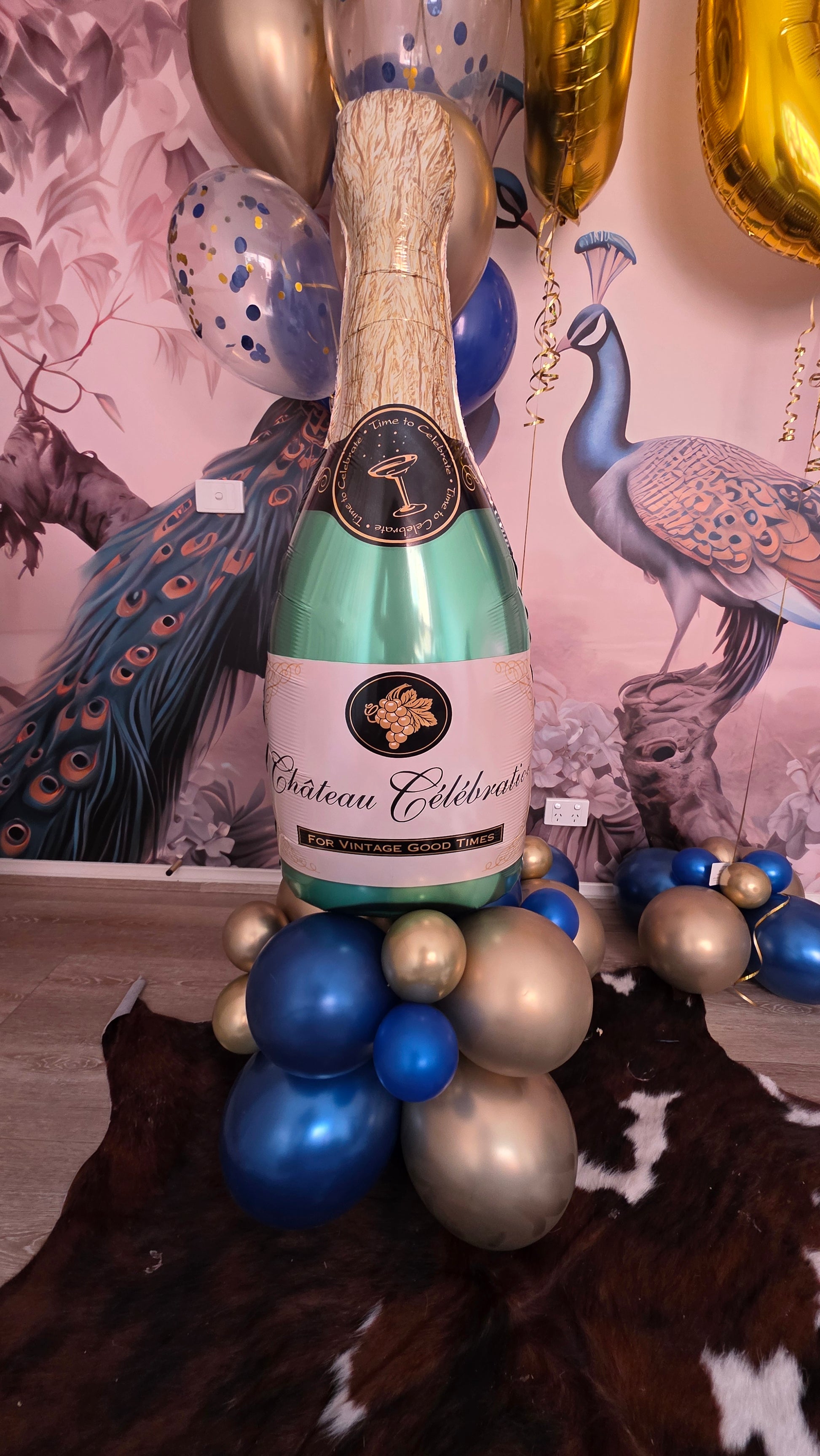Bottle of champagne with decorative balloons on a patterned surface