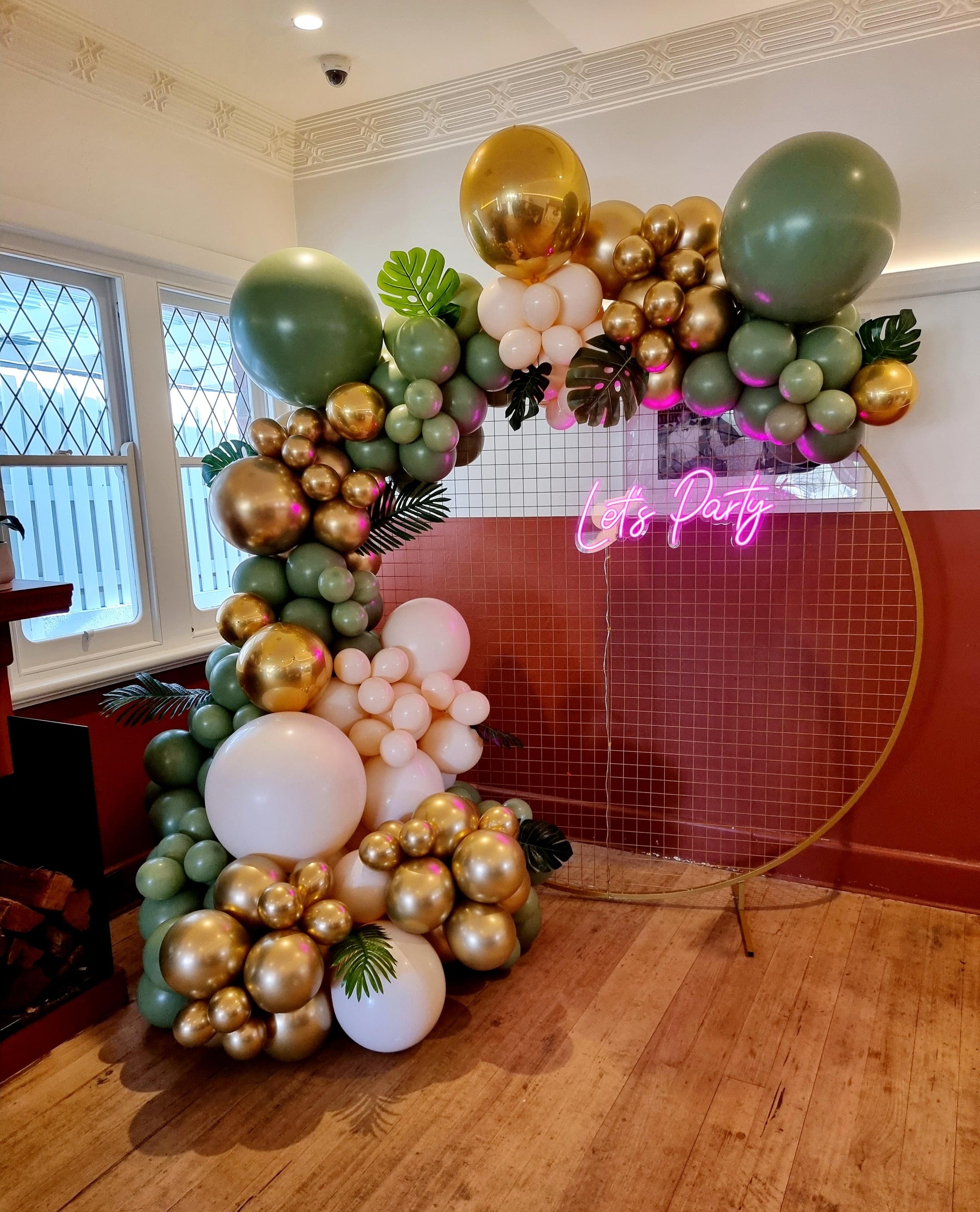 A DIY balloon garland kit featuring a mix of green, gold, and cream-colored balloons, arranged to form a decorative arch. Global Shipping from Australia