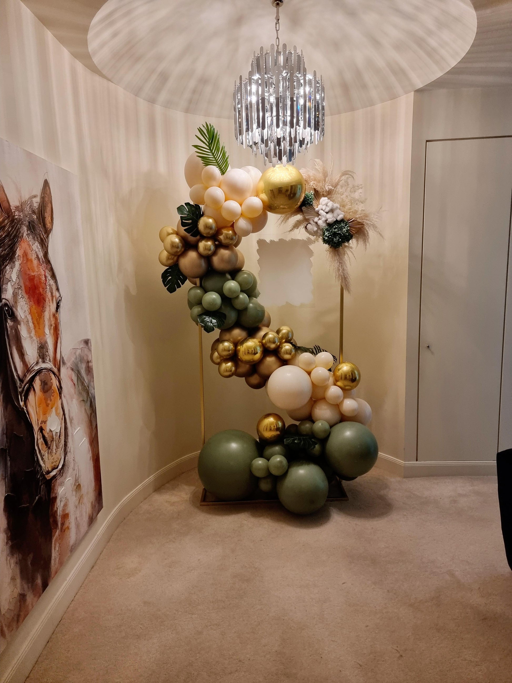 A DIY balloon garland kit featuring a mix of green, gold, and cream-colored balloons, arranged to form a decorative arch.