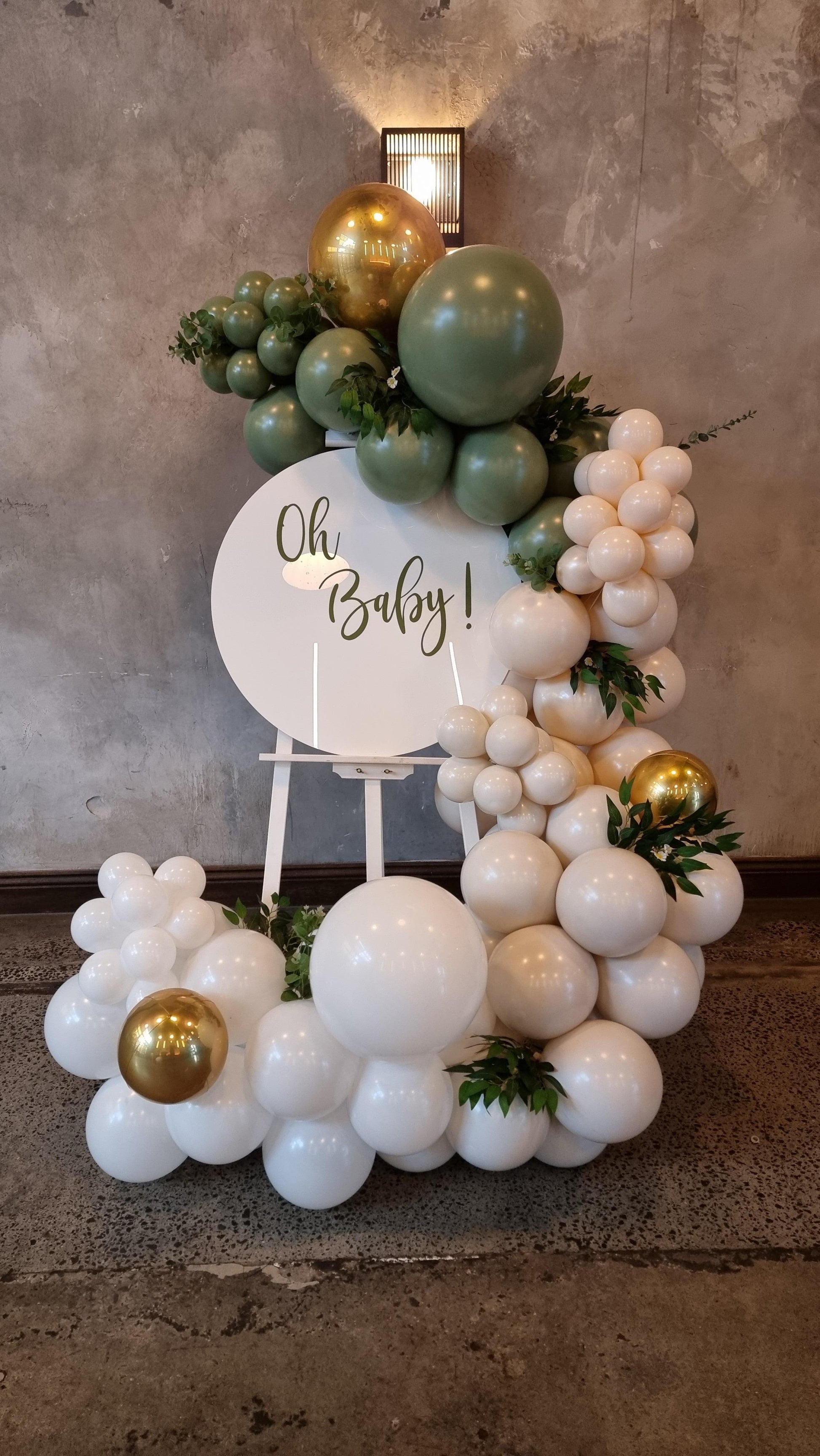 A DIY balloon garland kit featuring a mix of green, gold, and cream-colored balloons, arranged to form a decorative arch.