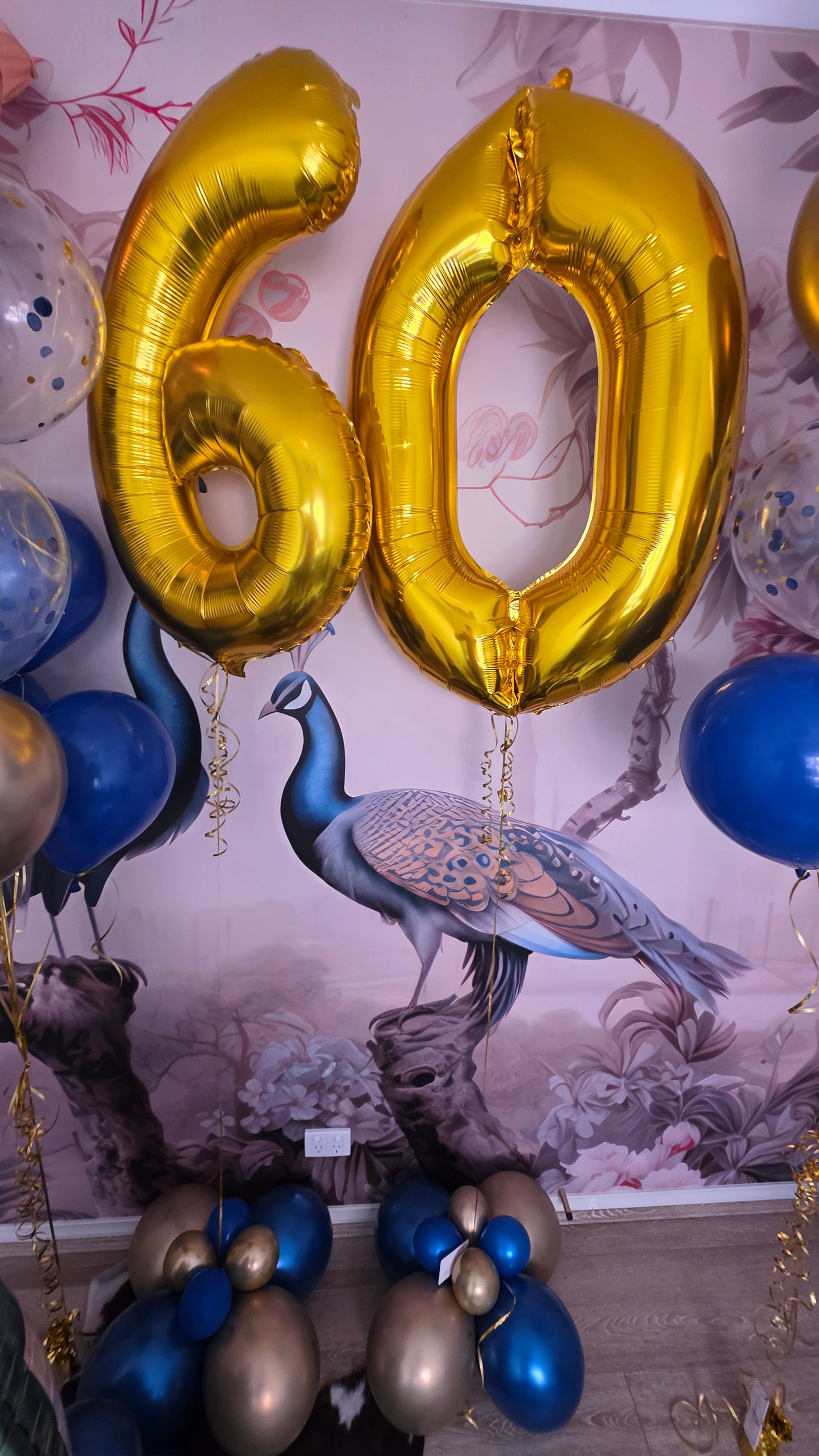 Gold number balloons on a decorative surface with peacock design