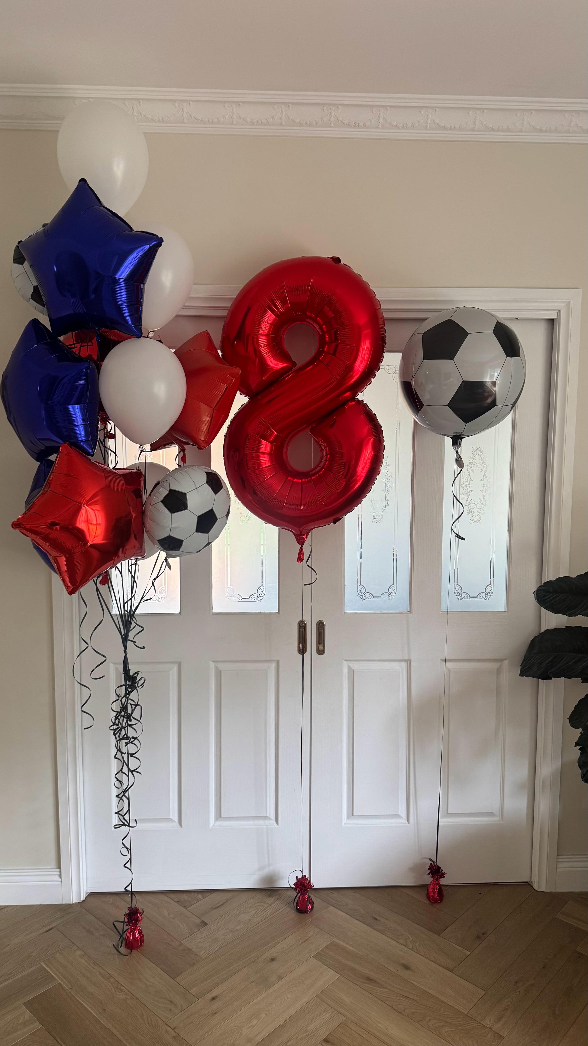 Decorative balloons with numbers and sports-themed designs on a wooden floor.