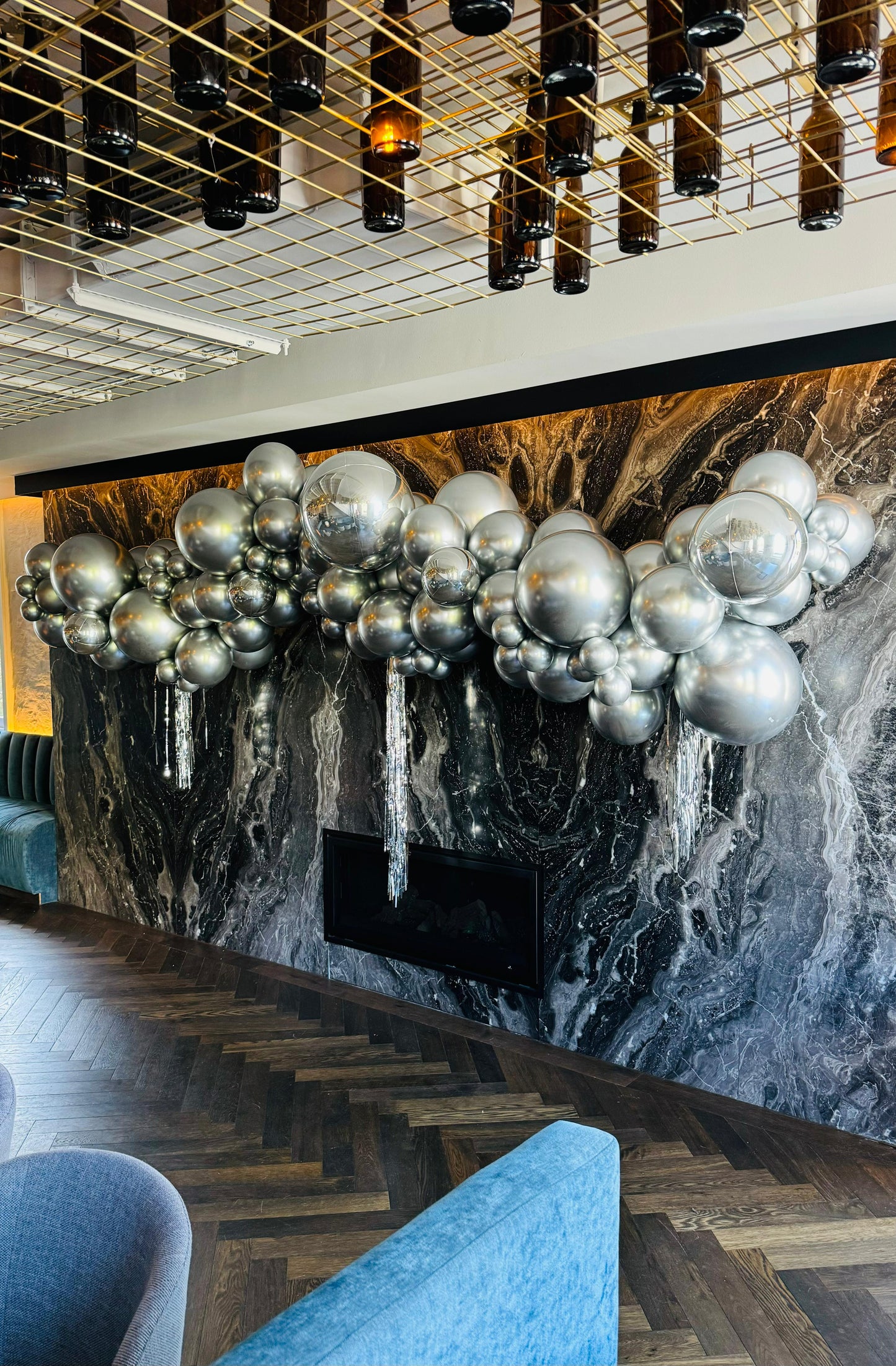 A building entrance decorated with a large, intricate balloon garland made of silver and foil balloons, with a video camera capturing the scene. Global Shipping from Australia. DIY Kit