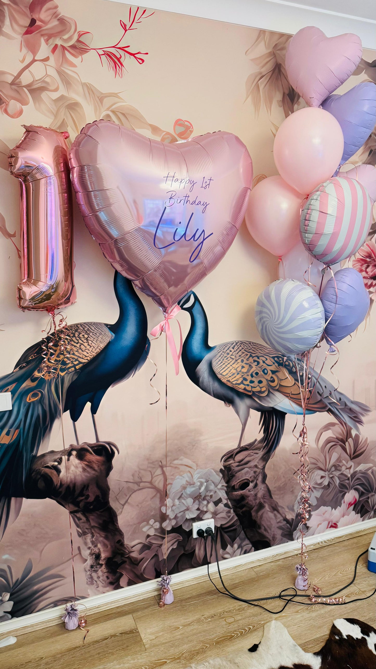 Decorative wall with peacock balloons and balloons shaped like numbers and letters.