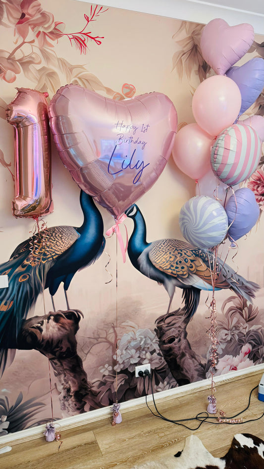 Decorative wall with peacock balloons and balloons shaped like numbers and letters.