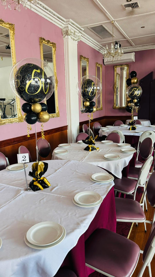 Dining room with tables set for a formal event, featuring balloons and decorations.