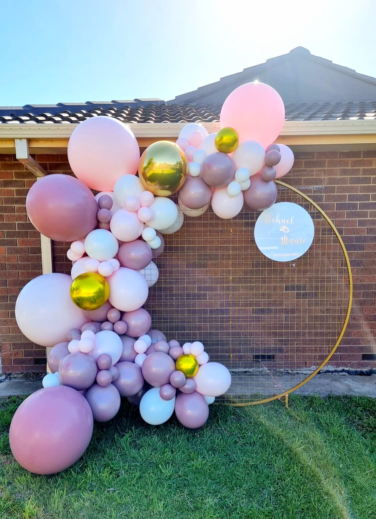 A garland made of pink, white, and rose colored balloons arranged in a circular pattern in front of a building.